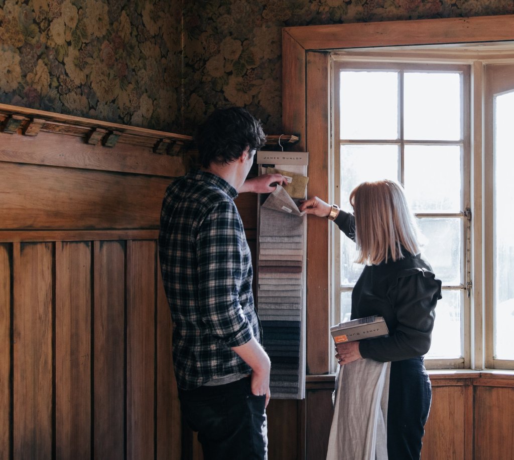A Russells consultant and customer reviewing fabric swatches in a panelled room.