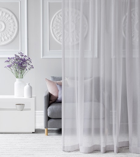 light grey sheer curtains in cosy modern lounge room on off white walls