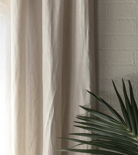 grey linen curtains on white brick wall with plant