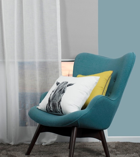 white sheer curtains and white blockout roller blind in contemporary sitting room on blue walls