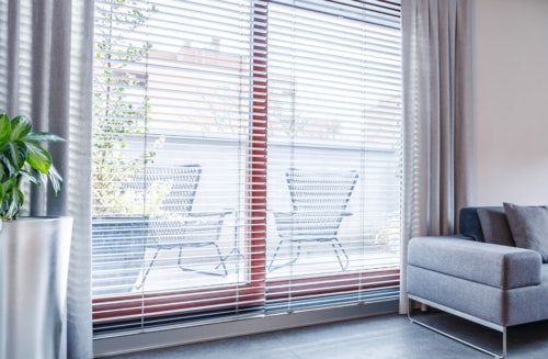 Large window with Russells venetian aluminum blinds next to couch