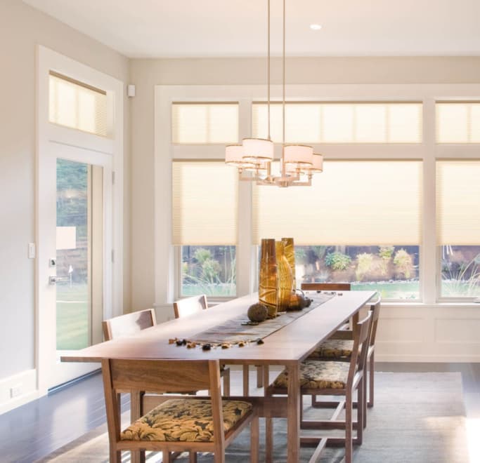 Dining room with table and chairs with Russells honeycomb blinds on large window