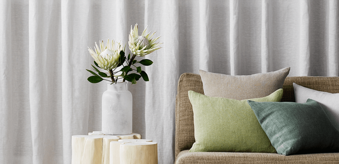 grey curtains behind brown couch