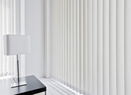 Large window with Russells Vertical blinds next to coffee table and lamp