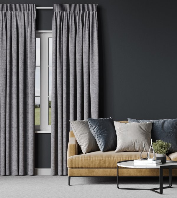Soft grey pencil pleat curtains drawn across a living-room window beside a mustard-yellow sofa.