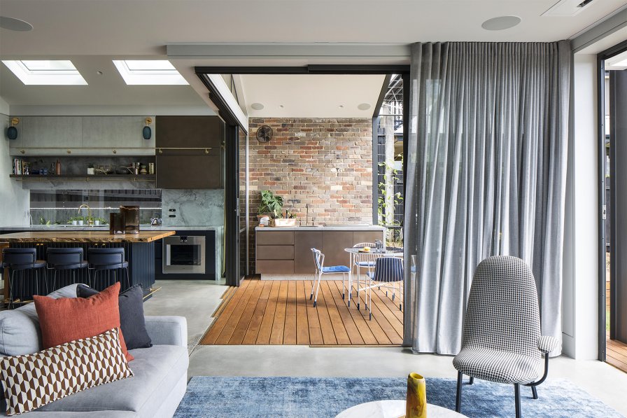 Full-length grey pinch pleat curtains across sliding glass doors in an open-plan home with a deck.