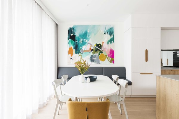 Light grey dining room with white roller blinds and beige curtains below a large landscape artwork.