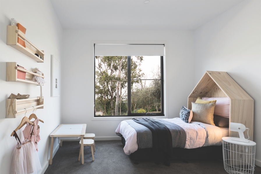 Child's bedroom with natural blinds fitted inside a black-framed window.