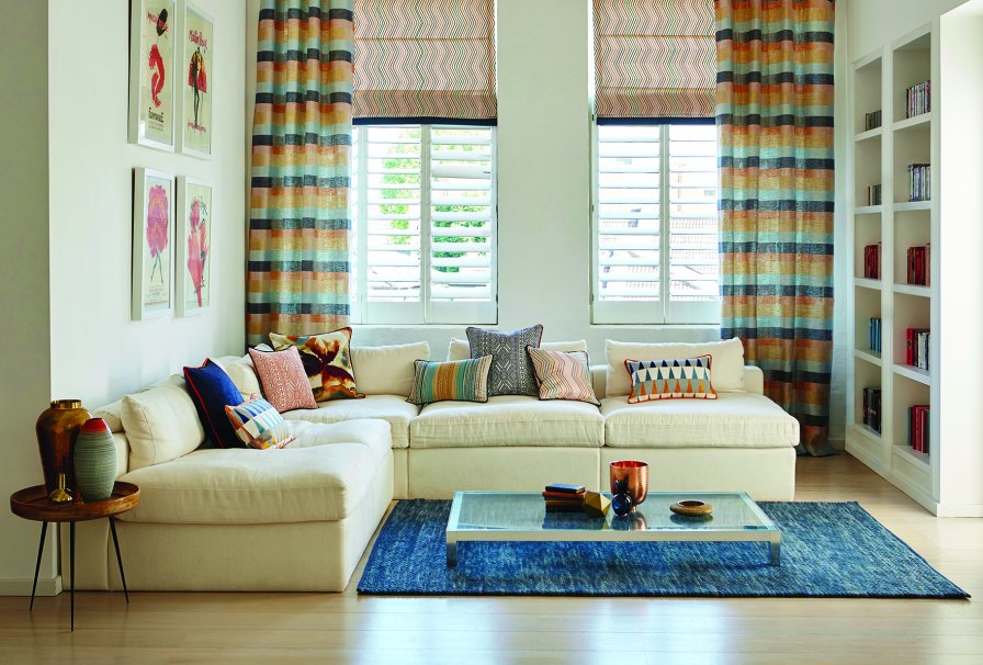 Coral, orange, blue and denim striped curtains and matching roller blind in a bright living room.