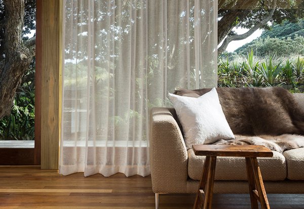 Sheer cream curtains diffusing light in a living room with garden views.