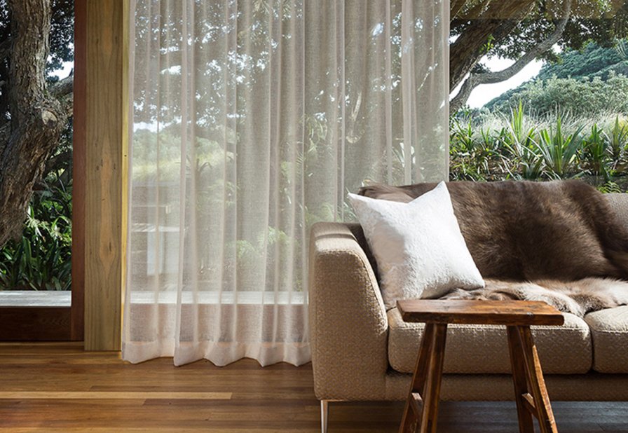 Sheer cream curtains diffusing light in a living room with garden views.