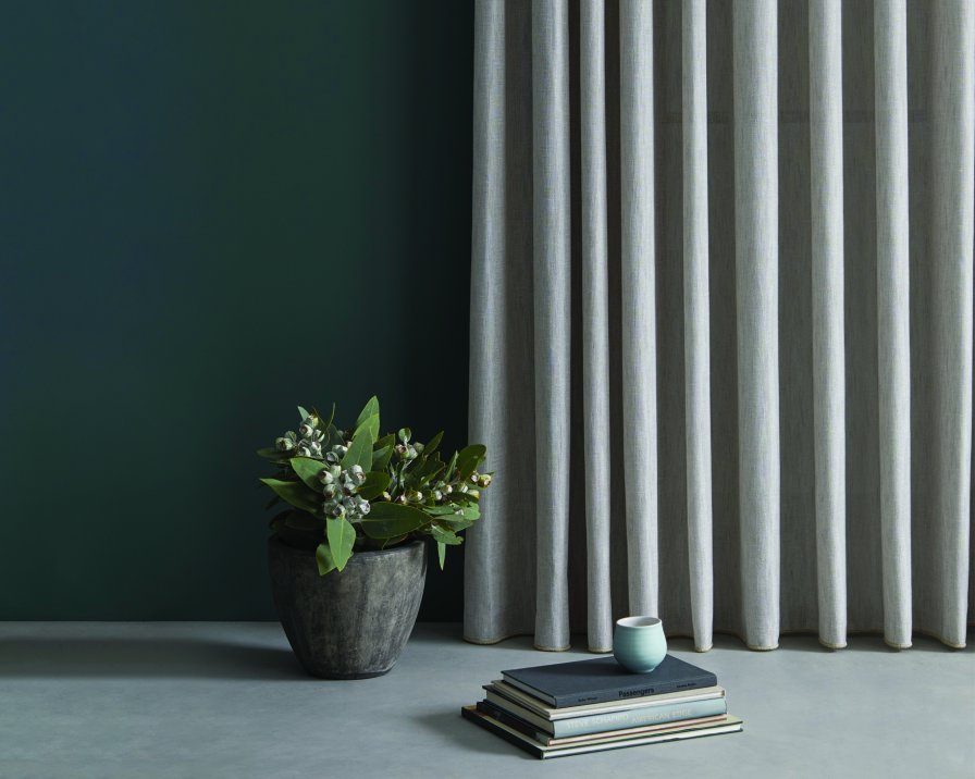 Soft grey striped curtains against a teal wall with a potted plant and books.
