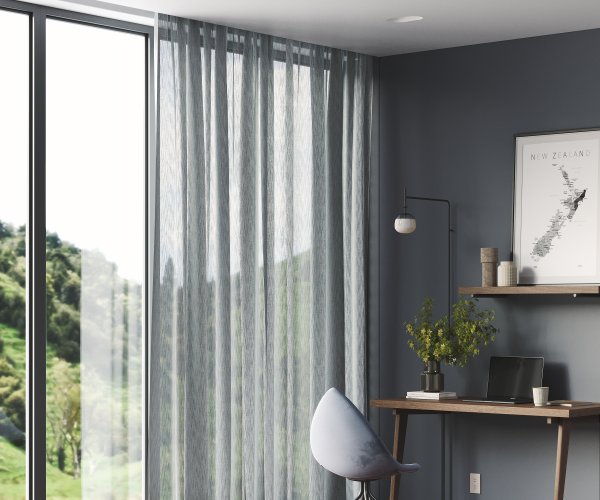 Beige and white striped sheer curtains and a roman blind on a large window in a grey study.