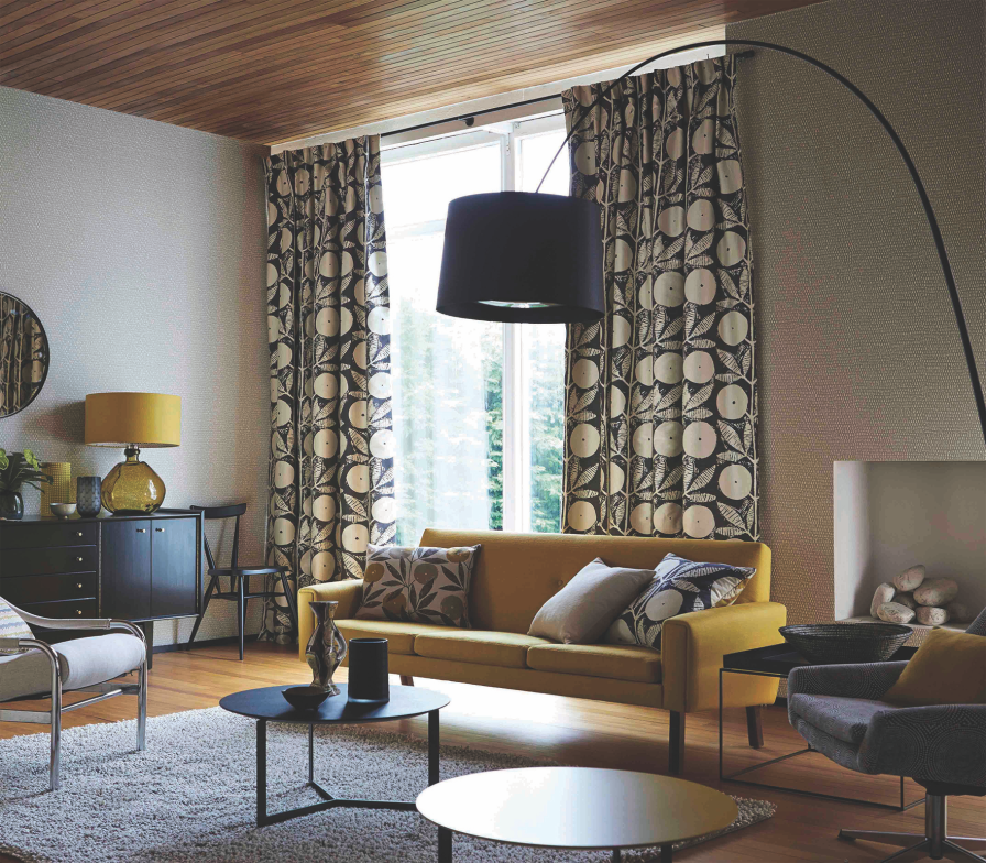 Tan and black geometric-circle patterned curtains in a living room with a yellow sofa and fireplace.