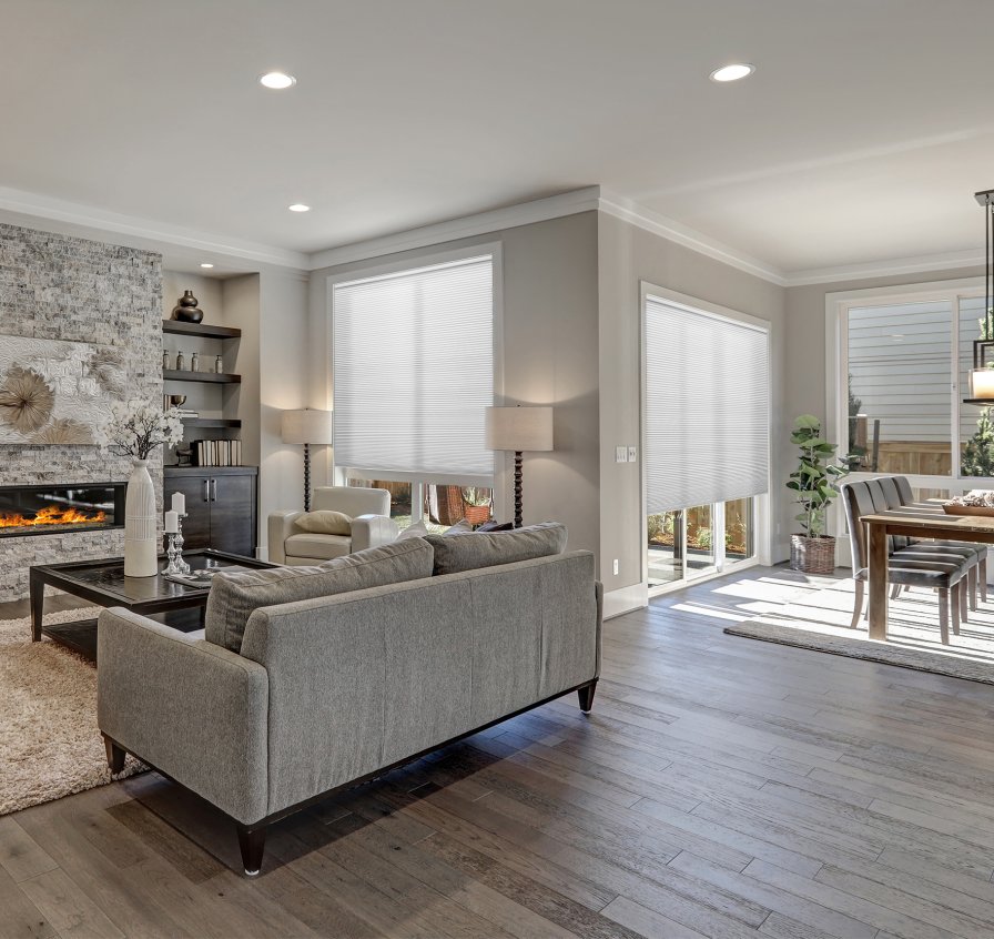 Living room with white honeycomb cellular blinds filtering light through large patio doors.