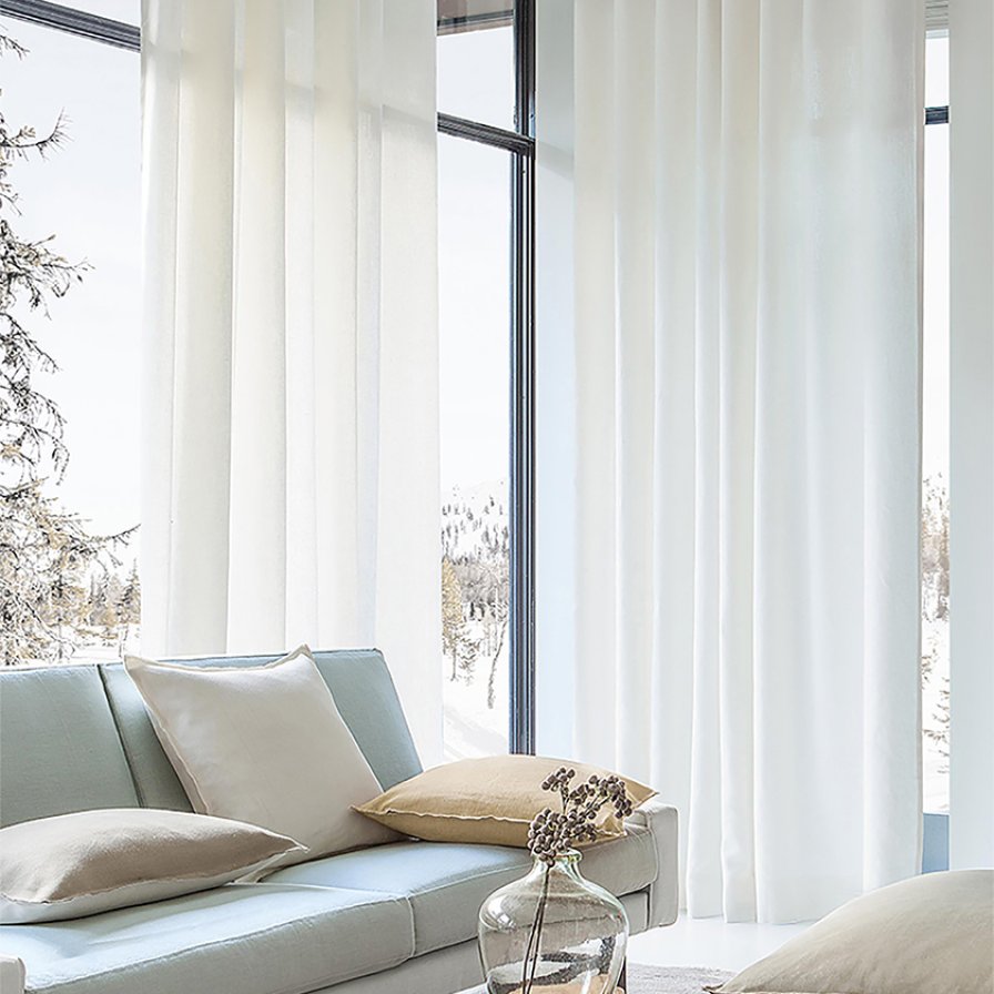 Floor-to-ceiling white sheer curtains on corner windows with a snowy forest view.