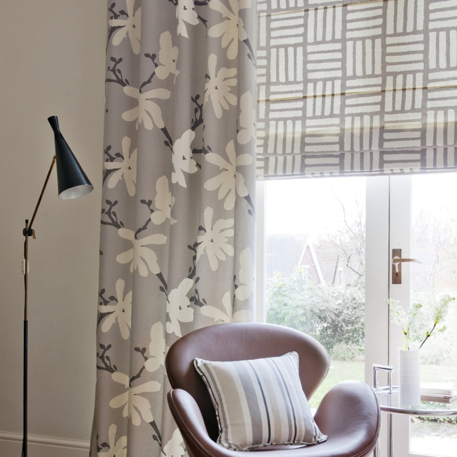 Bedroom with a taupe roman blind paired with sheer dove and blue curtains.