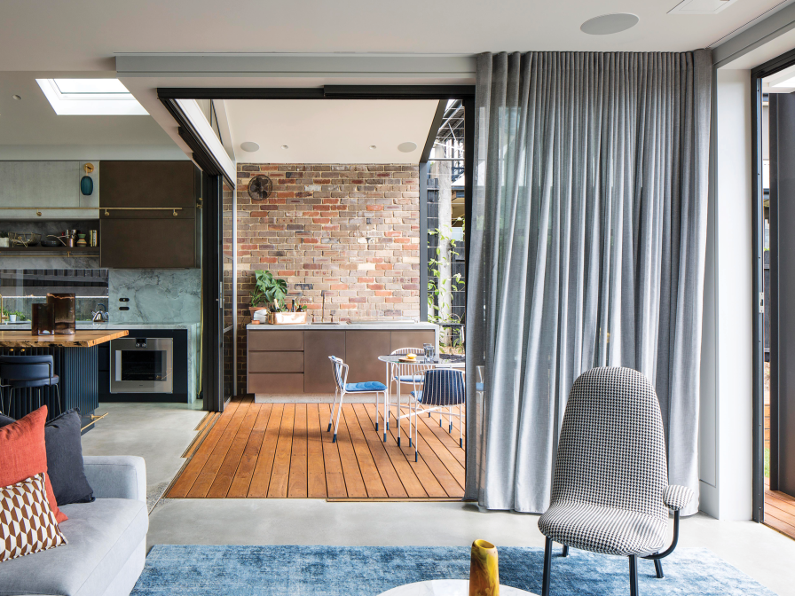 Open-plan space with grey ceiling-mounted curtains framing glass doors to a brick courtyard.
