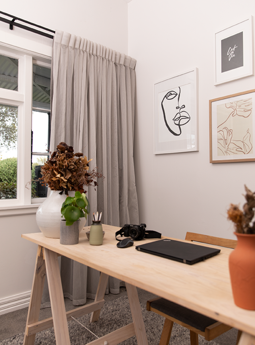 Home-office desk area with pale grey layered curtains diffusing bright natural light.