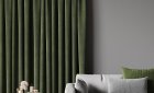Forest-green pleated curtains in a living room beside a white sofa and round side table.