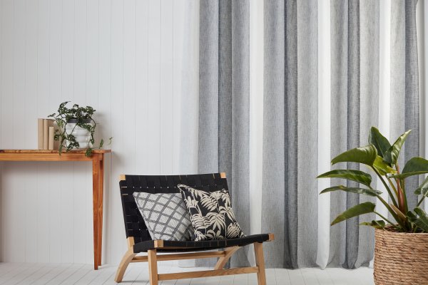 Grey and white vertical-stripe curtains by a wooden accent wall with a black lounge chair.