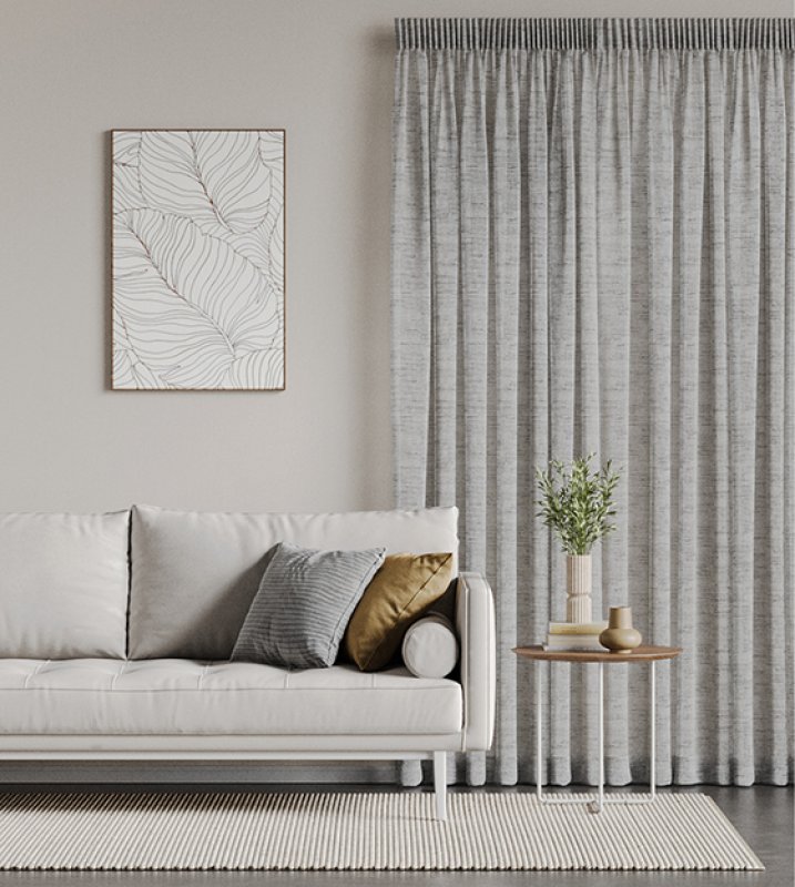 Light grey striped pencil pleat curtains beside a white sofa and side table.