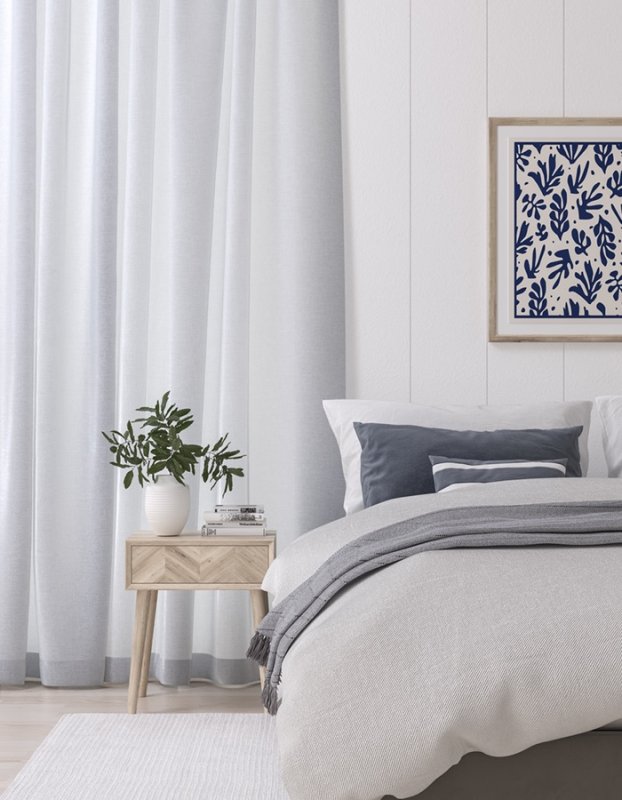 Pale blue-white curtains in a bedroom with a light wood bedside table and plant.