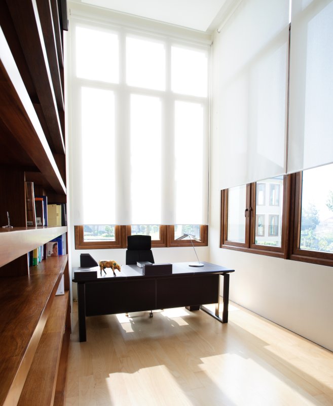 White roller blinds on tall windows in a light-filled office.