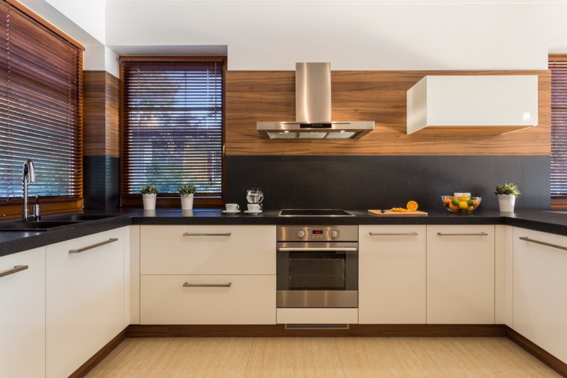 Charcoal-grey venetian blinds in a modern kitchen with white cabinetry.