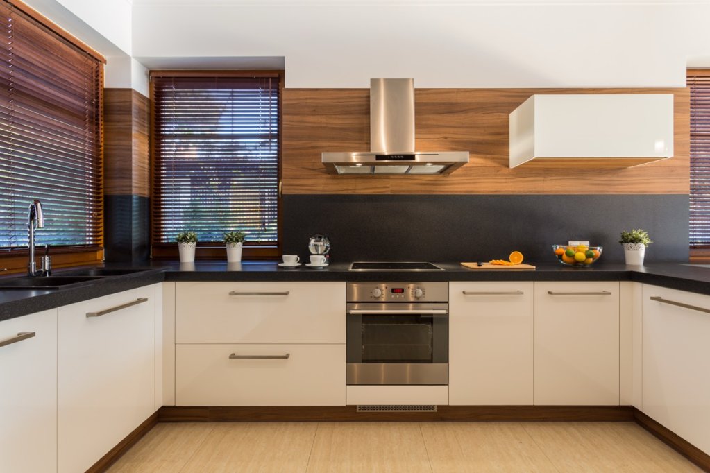 Charcoal-grey venetian blinds in a modern kitchen with white cabinetry.