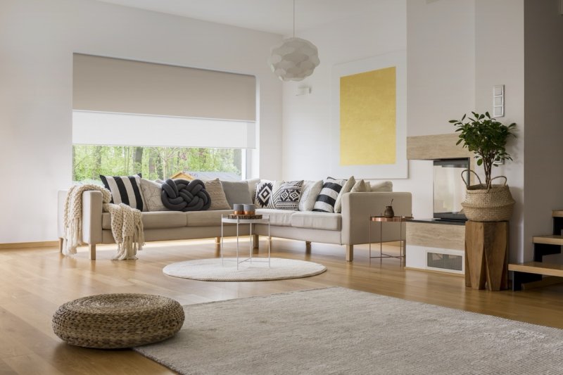 Beige dual roller blinds, sheer white upper and solid taupe lower, on a large living-room window.