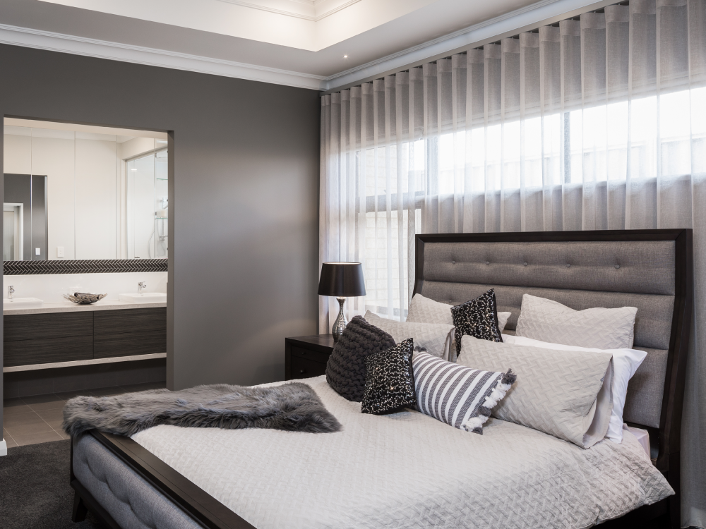 Bedroom with white and grey striped s-fold curtains above a grey headboard.