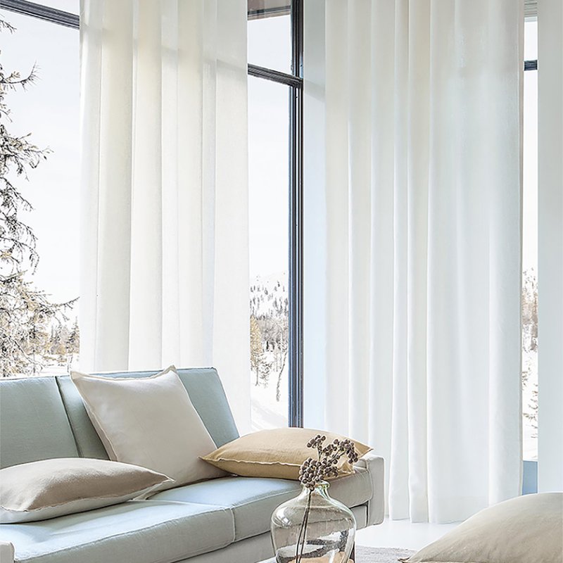 Floor-to-ceiling white sheer curtains on corner windows with a snowy forest view.