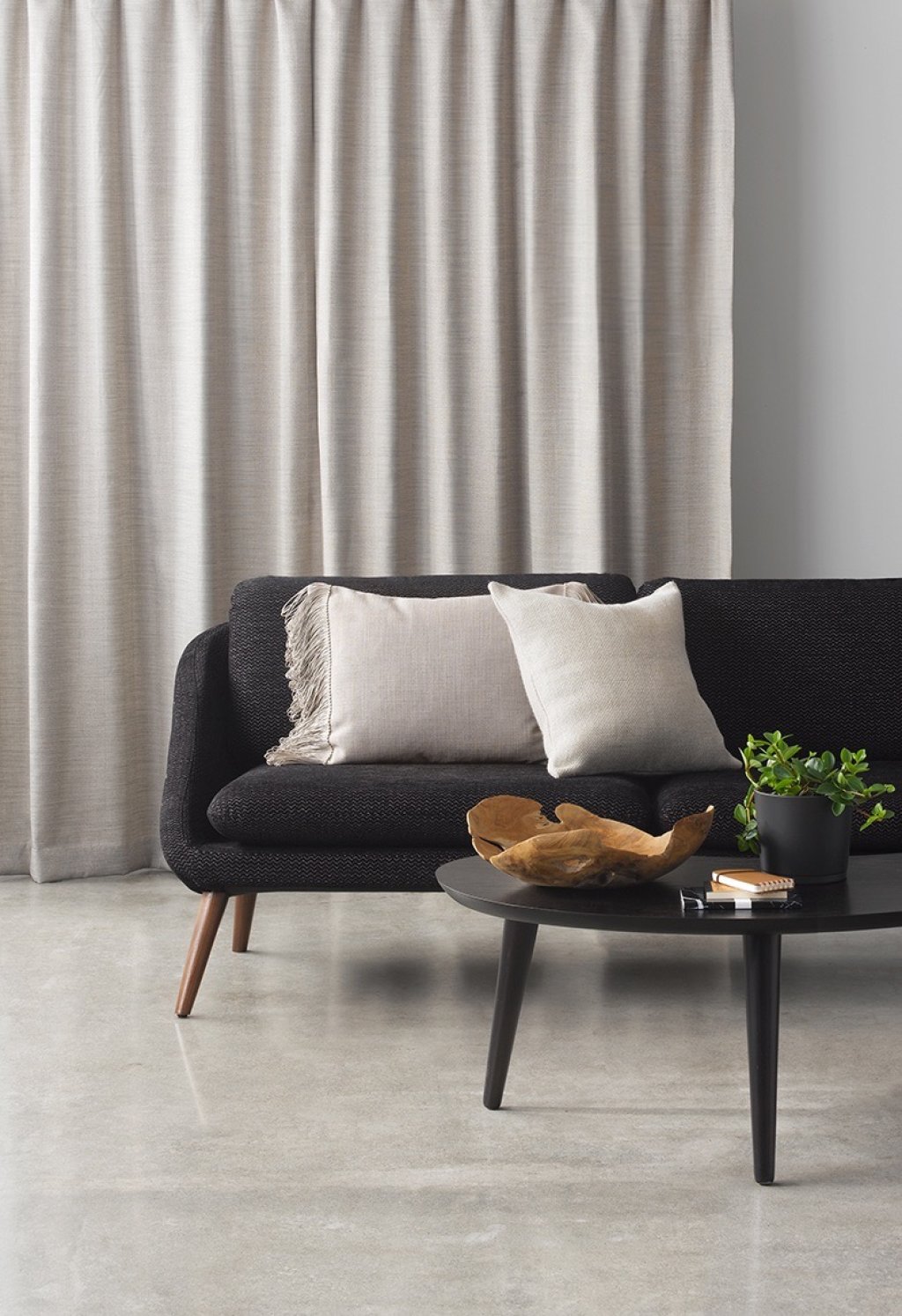 Taupe-grey linen curtains behind a cream and black sofa with contrasting cushions.