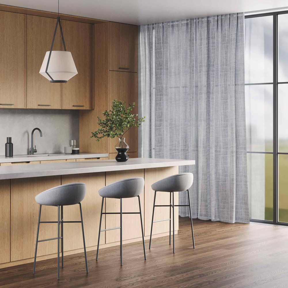Wooden kitchen with light grey curtains spanning a floor-to-ceiling window beside bar seating.