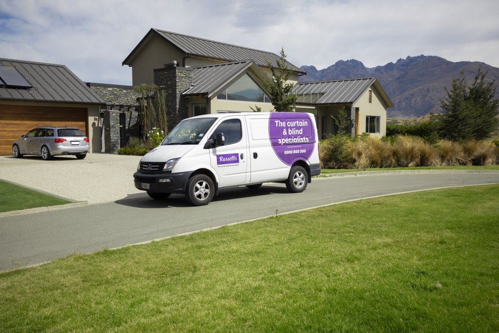 A Russells van in the driveway of a modern home with mountains behind, arriving for an in-home consultation.