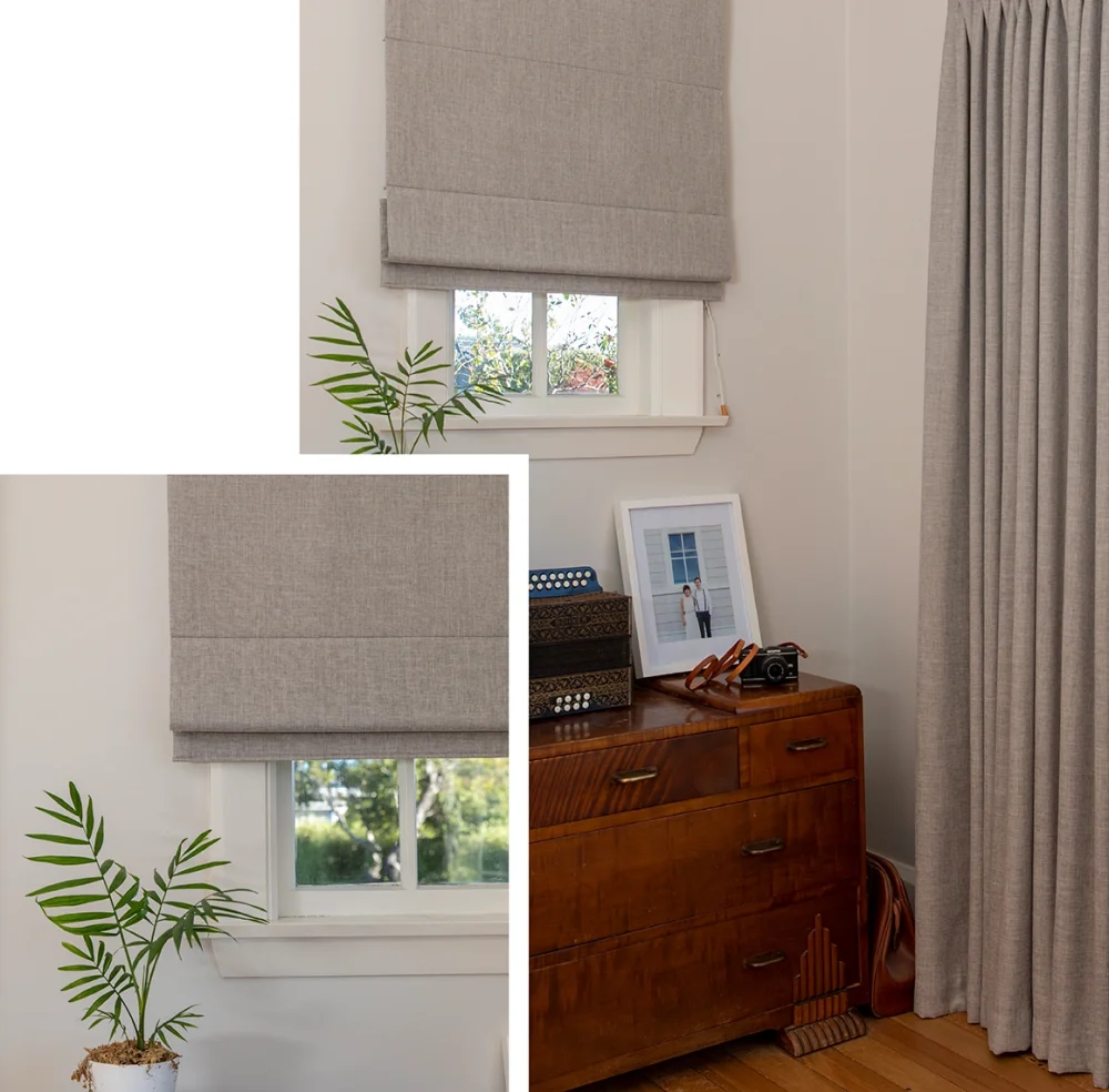 Taupe roller blinds at a sunlit window with a white sill and wooden furniture.