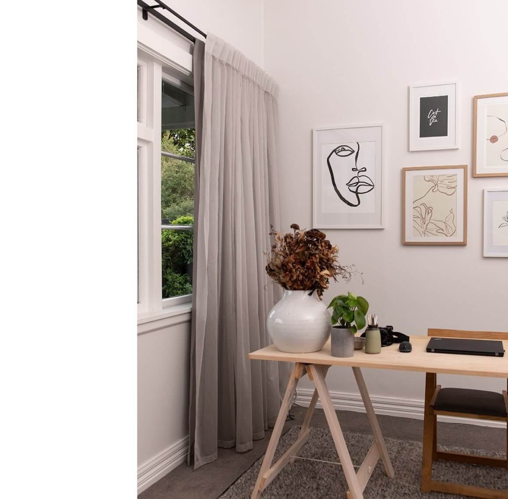 Pale grey sheer curtains by tall windows in a light-filled home office.