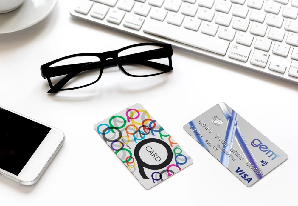 Q Card and Gem finance cards on a desk with a keyboard and glasses.