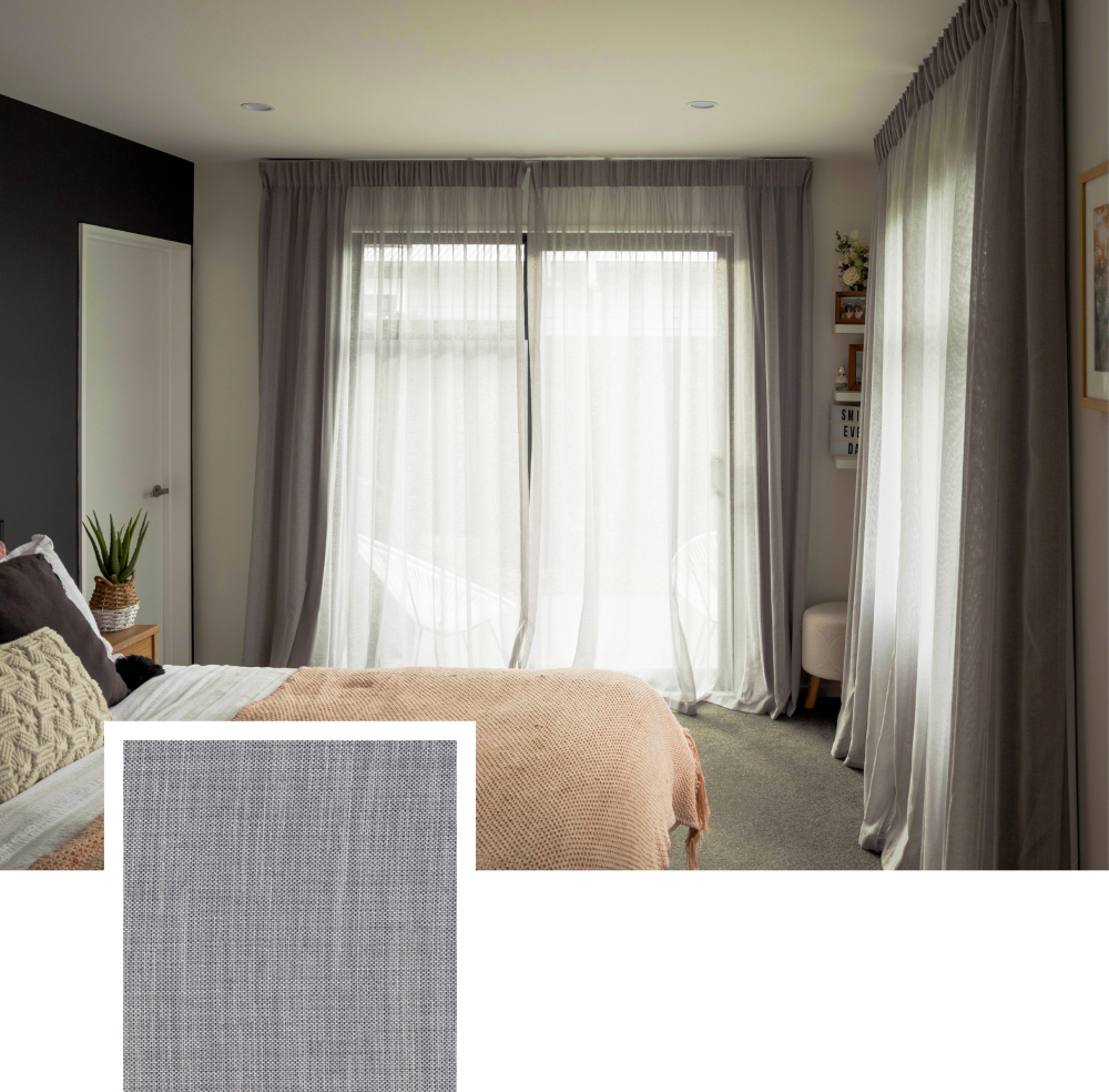 Bedroom with grey floor-to-ceiling curtains framing large windows and a cream bedspread.