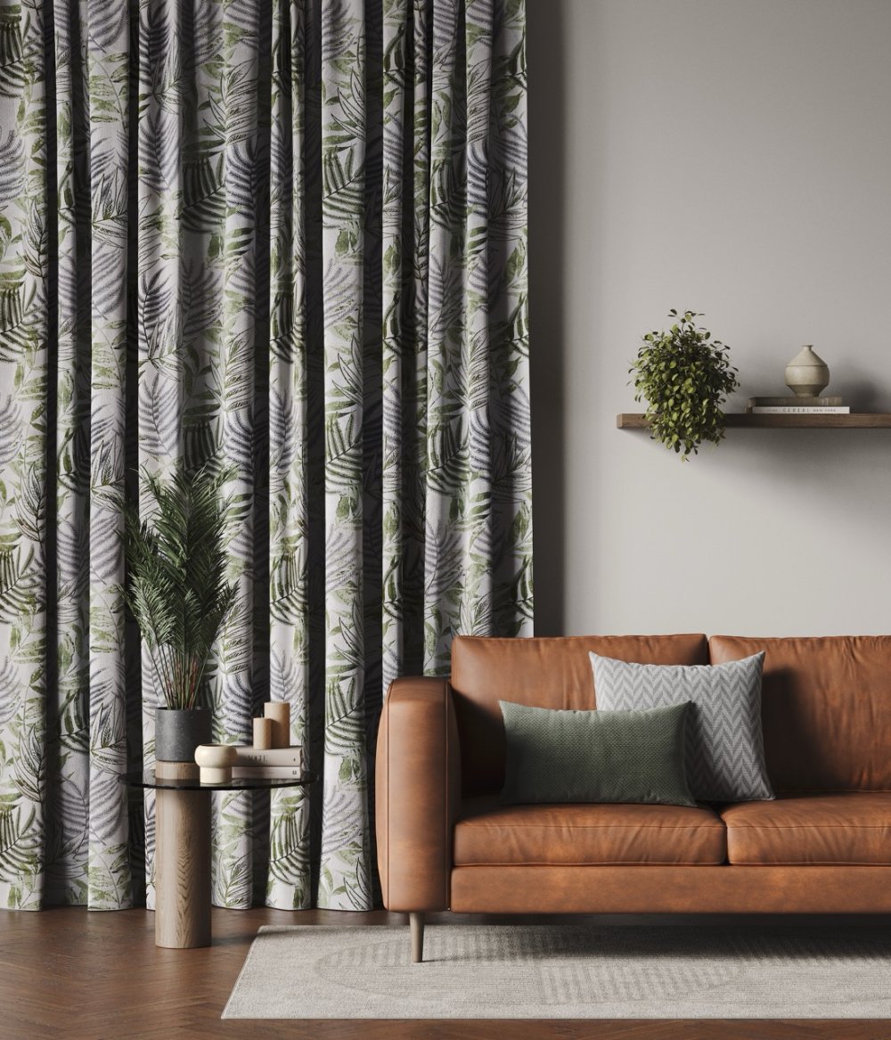Charcoal and cream tropical palm-print curtains beside a tan leather sofa.