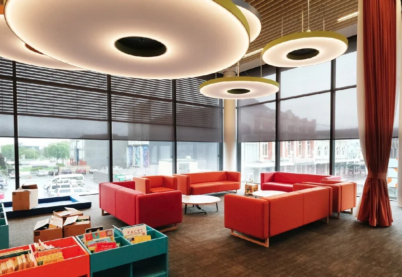 Modern library space with red curtains and red seating.