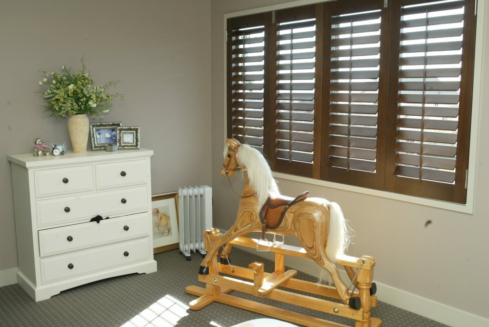 Brown timber shutters with white slats in a playroom with a rocking horse.