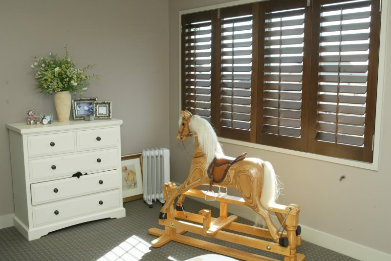 Brown timber shutters with white slats in a playroom with a rocking horse.