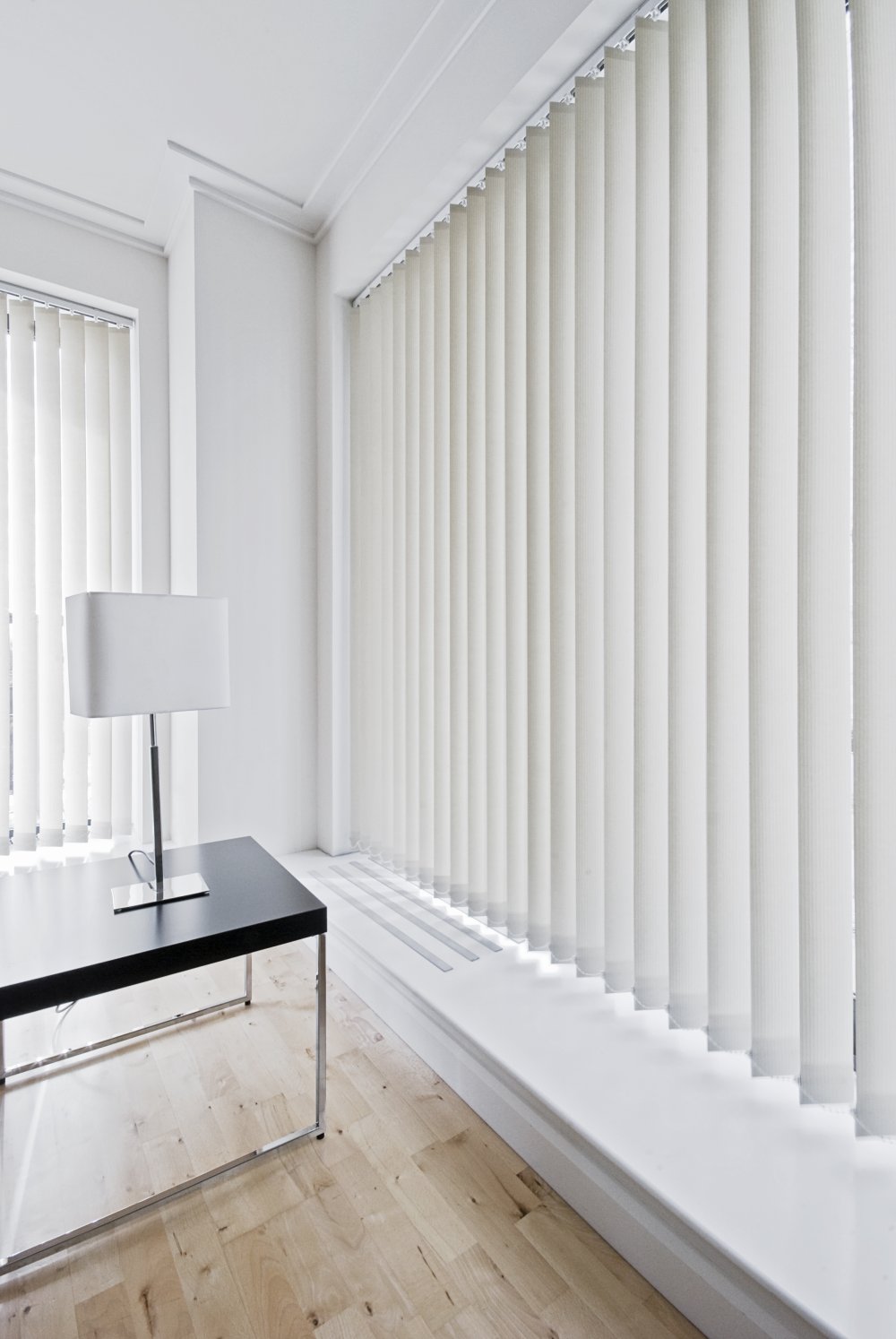 Bright office with white vertical blinds covering large windows.