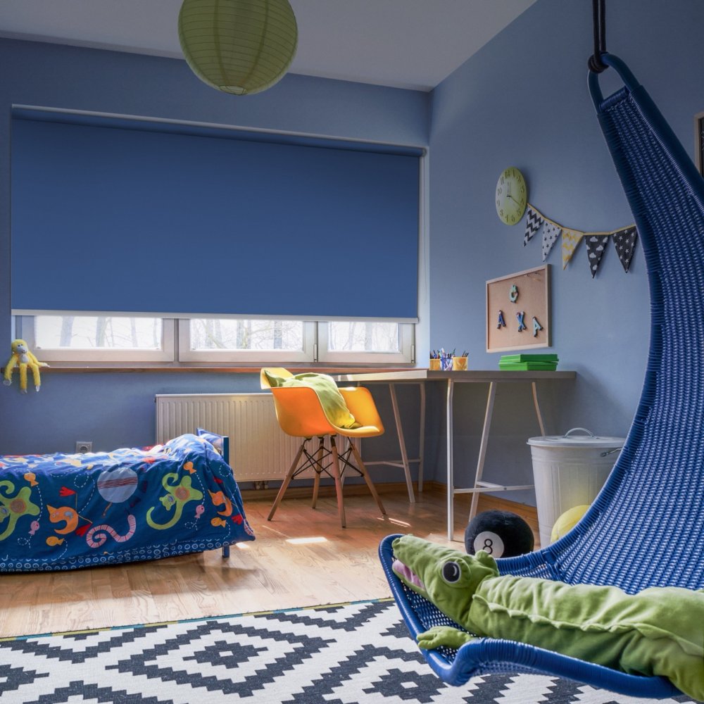 Blue blockout roller blind in a child's blue bedroom with a hanging chair and desk.