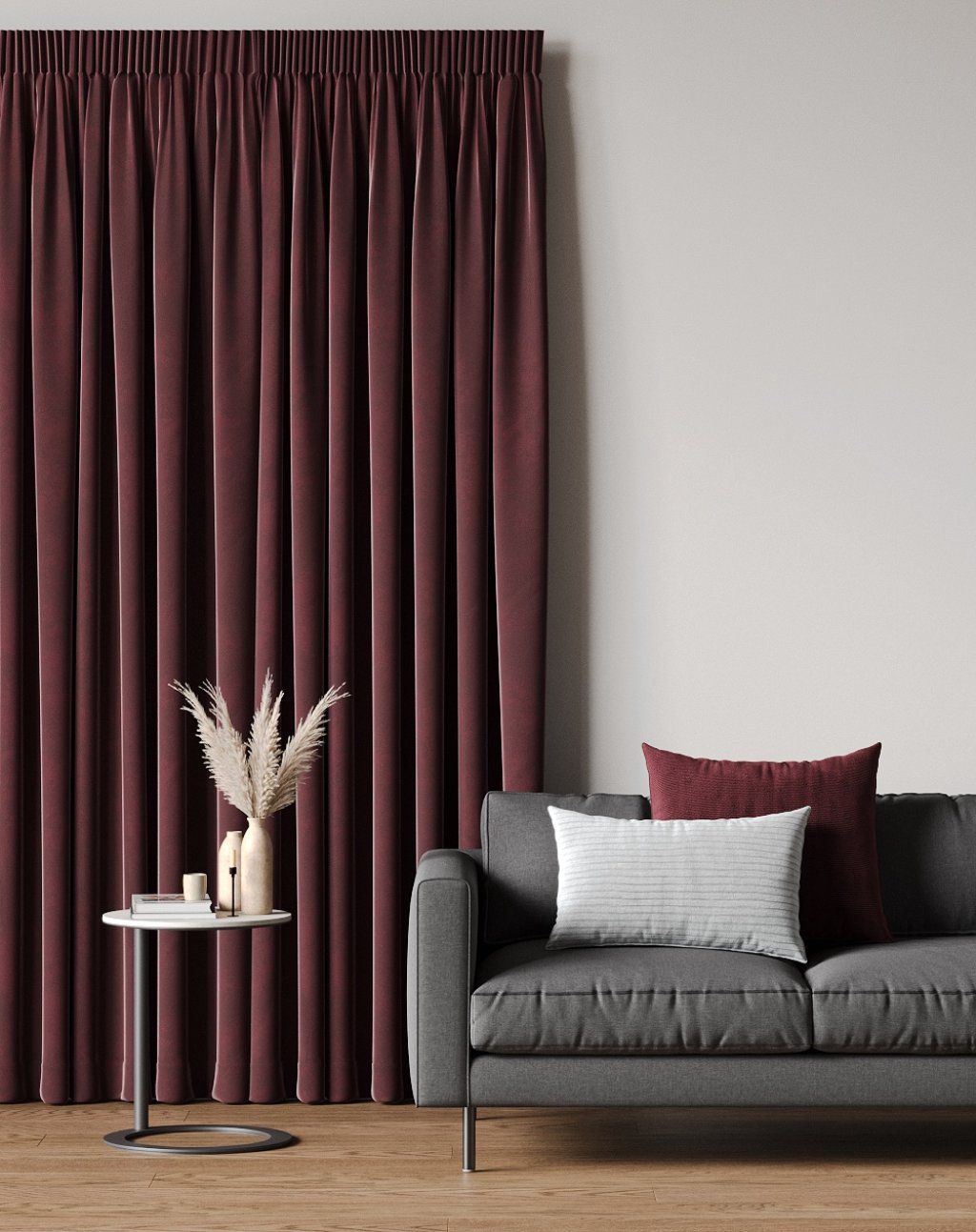 Deep burgundy velvet curtains with a pencil pleat heading beside a grey sofa.