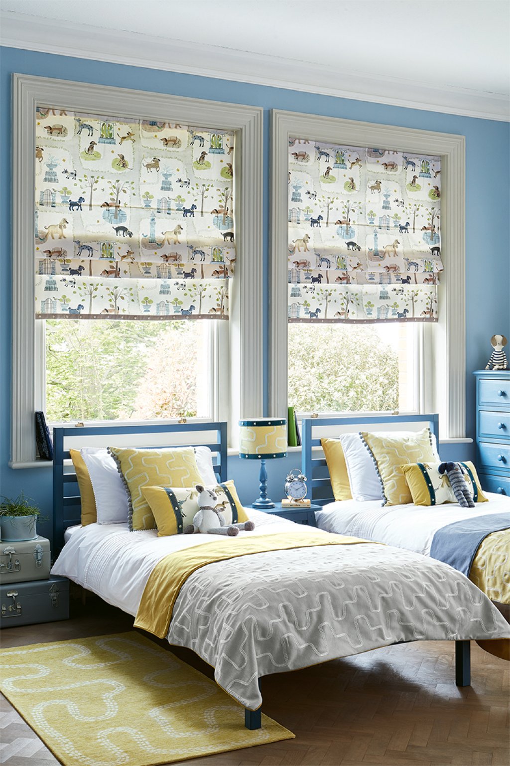 Child's bedroom with an animal-and-tree print roman blind and green wallpaper.